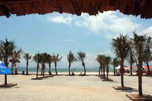 una playa con palmeras y gente sentada en la playa en Homestay sea view Newlife Halong., en Ha Long