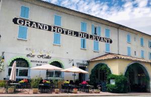 un hôtel avec des tables et des parasols devant lui dans l'établissement Hotel du Levant, à Castellane