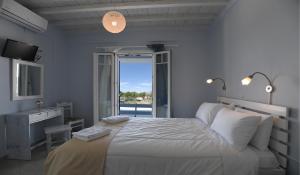 a white bedroom with a large bed and a window at Nostos Beachfront Apartments & Studios in Agios Ioannis