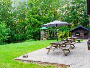 una mesa de picnic con sombrilla y parrilla en Lavish Holiday Home in Malmedy with Sauna en Longfaye