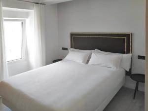 a white bed with white pillows and a window at Mar do Ézaro - Boutique Hotel in Ézaro