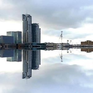 un reflejo de una ciudad en un cuerpo de agua en Sea Towers Apartamenty, en Gdynia
