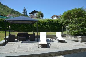 een groep stoelen en een parasol op een patio bij Sunshine-bnb in Aosta