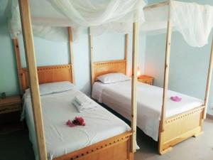 Dos camas en un dormitorio con flores. en Can Teranga en Kafountine