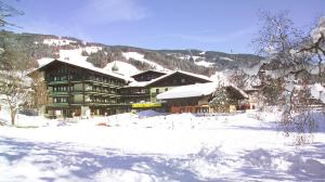 een groot gebouw met sneeuw op de grond voor de deur bij Unterwirt in Saalbach Hinterglemm