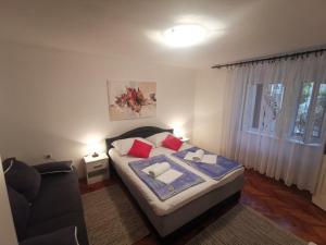 a bedroom with a bed and a couch and a window at Apartment Dino in Novi Vinodolski