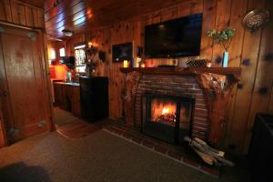 a living room with a fireplace with a tv on top at Sleepy Hollow Cabins & Hotel in Crestline