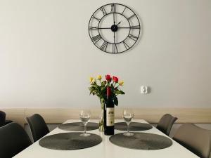 a table with two glasses and a clock on the wall at Apartament Toscania in Kołobrzeg