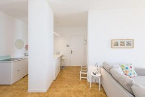 een witte woonkamer met een bank en een keuken bij Appartamento in posizione centrale con vista mare e parcheggio in Caorle