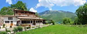 une grande maison dans un champ à côté d'un lac dans l'établissement Agriturismo Miralago, à Scanno