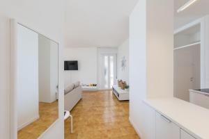 een woonkamer met witte muren en houten vloeren bij Appartamento in posizione centrale con vista mare e parcheggio in Caorle