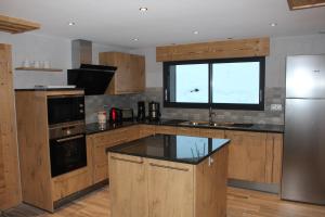 een keuken met houten kasten en een groot raam bij chalet bel horizon La Montagne Des Lamas in La Bresse +14 foto's