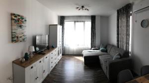 ein Wohnzimmer mit Sofa und Fernseher in der Unterkunft Sunny Shore Burgas Apartment in Burgas City