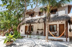 a house with a hammock in front of it at Tierra del Mar Hotel - Adults Only in Holbox Island