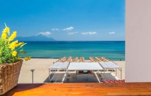 una mesa y sillas en una playa con el océano en House Kostas on the beach, en Sarti