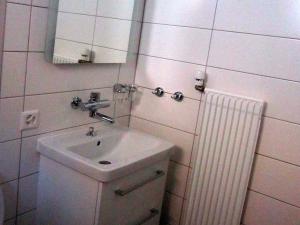 uma casa de banho com um lavatório, um espelho e um radiador em Flumina - Ferienwohnung für max. 4 Personen em Flims