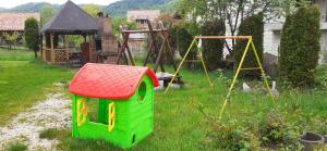 un parque infantil con una casa verde y columpios en un patio en Pensiunea Ando, en Bran