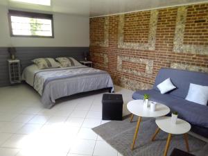 1 dormitorio con cama, sofá y pared de ladrillo en Domaine de Pimont, en Yerville