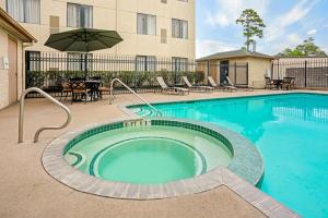 a swimming pool with an umbrella next to a building at La Quinta by Wyndham Houston North-Spring in Spring
