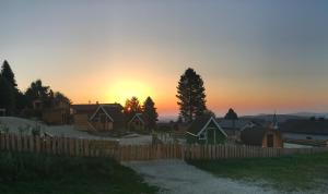 una puesta de sol sobre una valla de madera y casas en Glamping Park, en Mönichkirchen