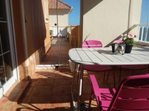 a white table and pink chairs on a balcony at Las Arenas 112 - Atico vista al mar in Isla Canela