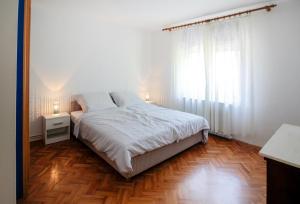 um quarto com uma cama branca e piso em madeira em Apartment Šverko em Kastav