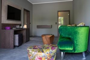 a living room with a green chair and a stool at Motel24 in Rietberg