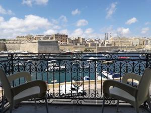 a balcony with two chairs and a view of a city at Villa Del Porto in Kalkara