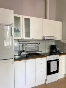 una cocina con armarios blancos y fregadero en Willa Strand, en Kristinestad