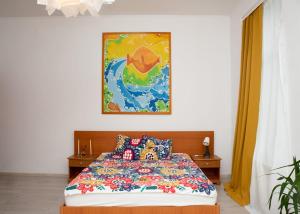 1 dormitorio con 1 cama con una pintura en la pared en Pensiunea Lms, en Brăila