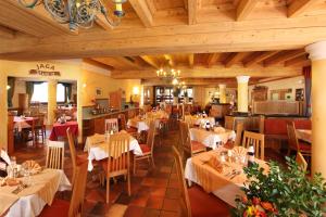 un ristorante con tavoli e sedie bianchi e soffitti in legno di Unterwirt a Saalbach Hinterglemm