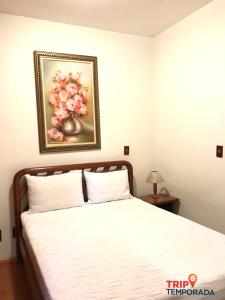 una camera da letto con un letto e un dipinto sul muro di Apartamento a 300 metros do centrinho do Capivari - Residencial La Villete a Campos do Jordão