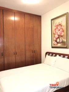 una camera con letto e armadio in legno di Apartamento a 300 metros do centrinho do Capivari - Residencial La Villete a Campos do Jordão