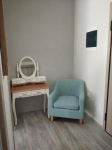 a room with a blue chair next to a desk with a mirror at HILI RESORT LUXURIOUS SEASIDE APARTMENT in Alexandroupoli