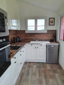 a kitchen with white cabinets and a sink at Gîte de la Maison du L.A.C in Simard