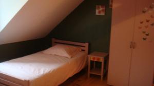 - une petite chambre avec un lit et un mur vert dans l'établissement Les Gallerands, à Bessais-le-Fromental