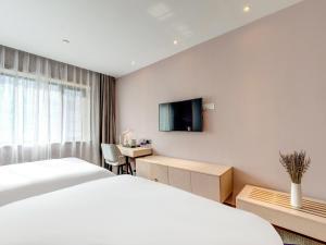 una camera d'albergo con letto, scrivania e TV di Lavande Hotel Tianjin Joy City Gulou Subway Station a Tianjin
