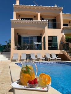 a tray with a pitcher of juice and fruit next to a swimming pool at Casa das Roseiras in Ferragudo