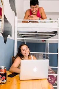 a woman sitting at a table with a laptop at Rising Cock Party Hostel in Lagos