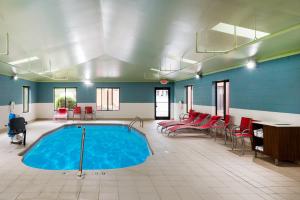 a swimming pool in a room with red chairs and a table at Holiday Inn Express Hillsville, an IHG Hotel in Hillsville