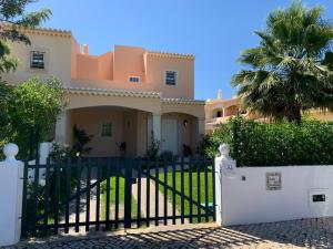 a house with a gate and a palm tree at Casa das Roseiras in Ferragudo