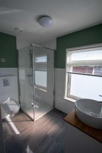 ZuidzandeにあるThe Town hotel studios appartmentsのバスルーム(ガラス張りのシャワー、シンク付)