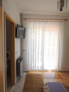 een woonkamer met een groot raam met witte gordijnen bij Apartmani Šutić in Promajna
