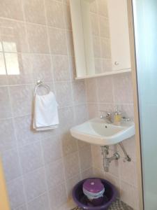 een badkamer met een witte wastafel en een paarse kruk bij Apartmani Šutić in Promajna