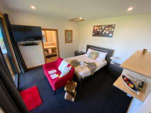 a hotel room with a bed and a red chair at Tasman Sea Retreat in Punakaiki