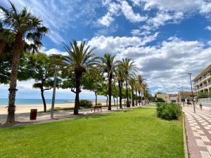 a park with palm trees and the beach at House in front of the beach with sea view in Cambrils