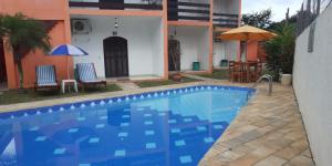 a blue swimming pool in front of a house at VILLA GARDEN - Suites in Maresias