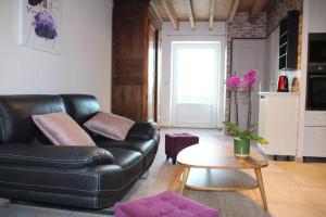 a living room with a black leather couch and a table at Cottage Le Phare - Le Clos de la Morière in Mont-Dol
