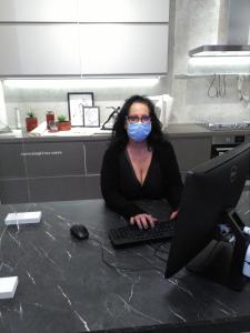a woman wearing a mask sitting at a table with a computer at Hotel Gloria in Rome