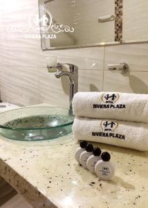 a bathroom with a sink and a mirror and towels at Hotel Riviera Plaza in Bucaramanga